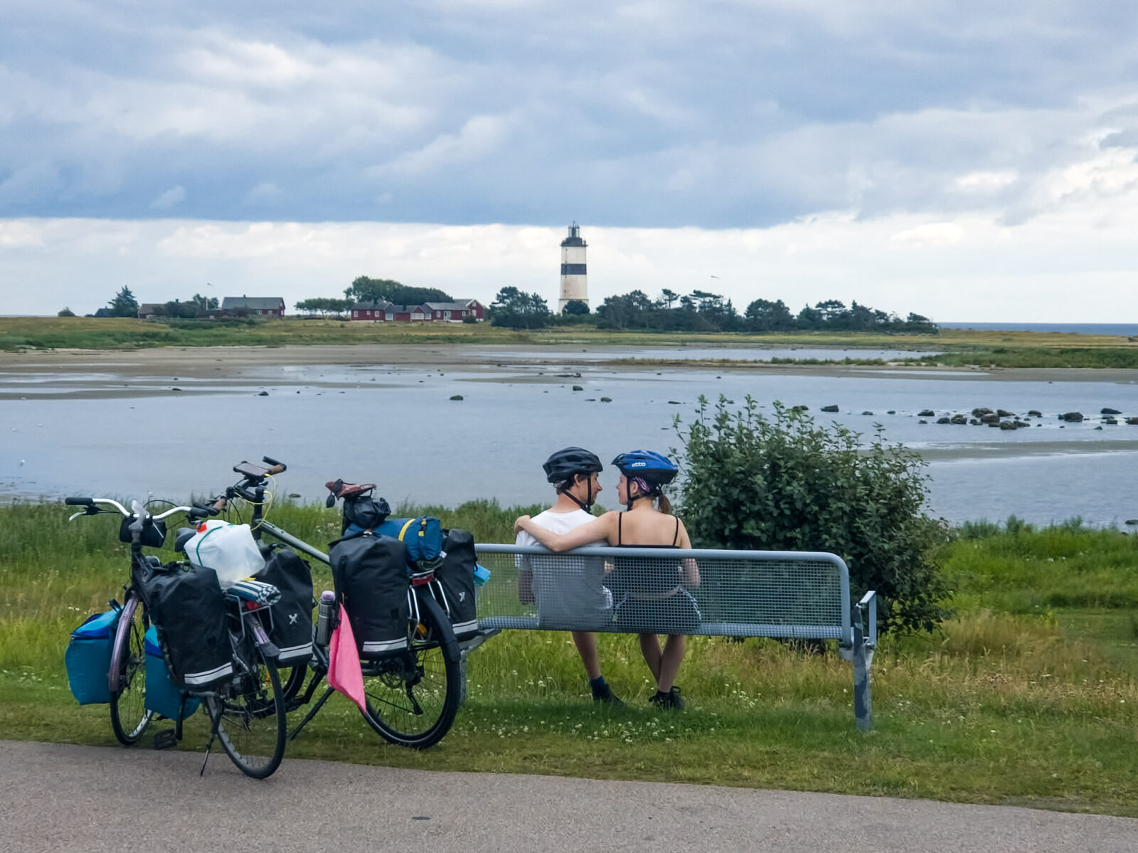 Fietsers pauzeren op een bankje aan het water met uitzicht op de stad